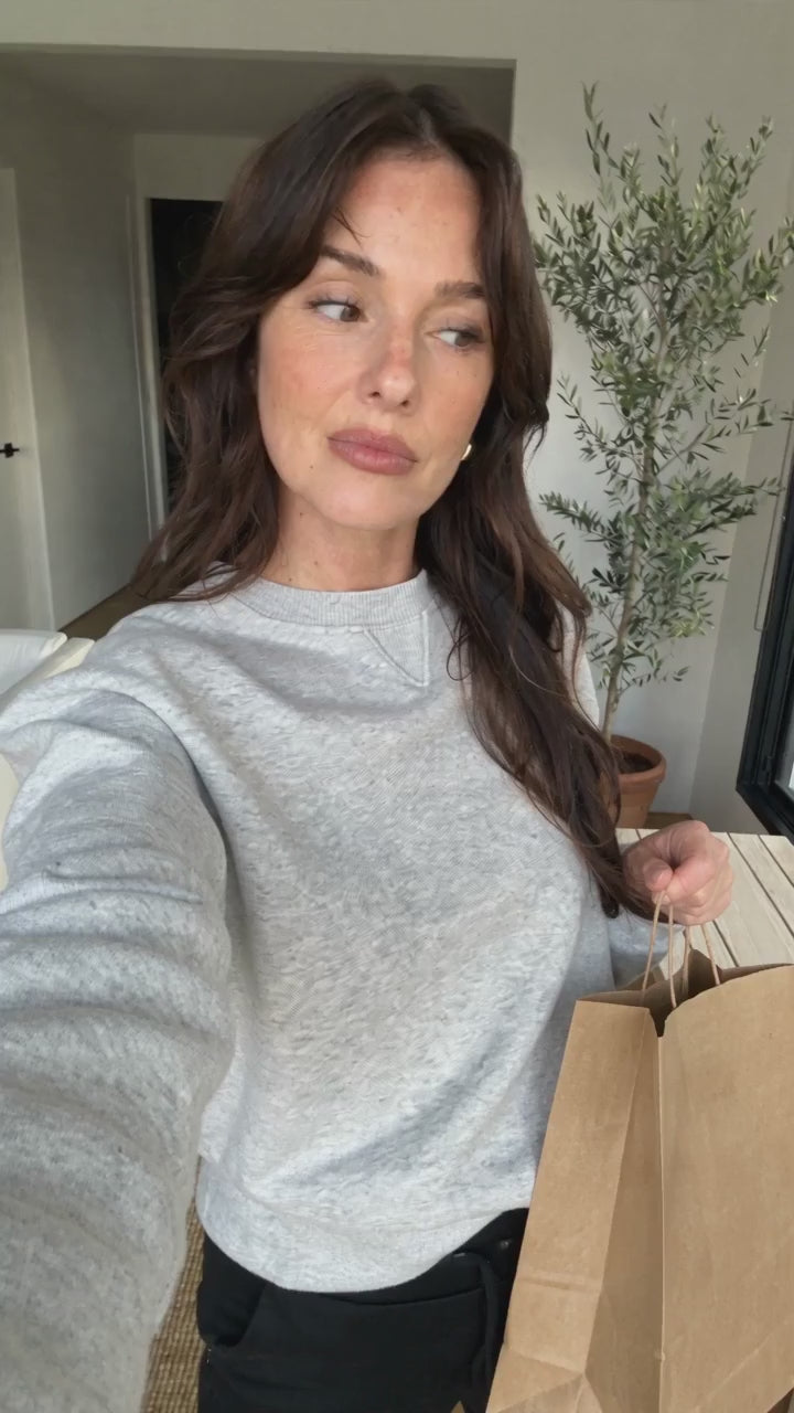 AI-generated presenter wearing the black Everyday Tank with built-in bra on its own and under a cardigan